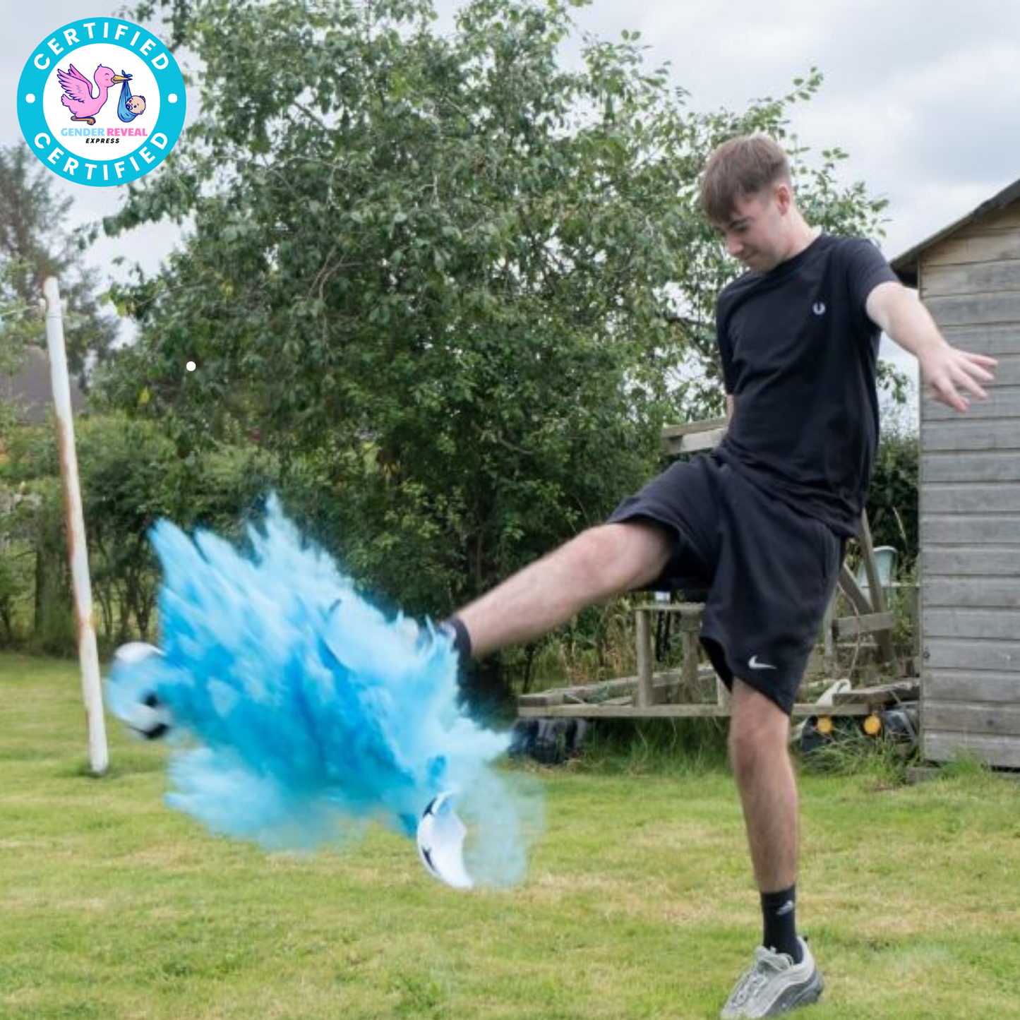 Boy kicking Gender Reveal Soccer Ball with blue powder explosion during reveal event