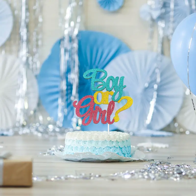 Boy or Girl? cake topper on a gender reveal cake with blue decorations and balloons in the background.