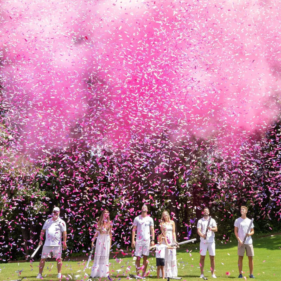 Family using Gender Reveal Confetti and Powder Cannon with pink smoke in a park