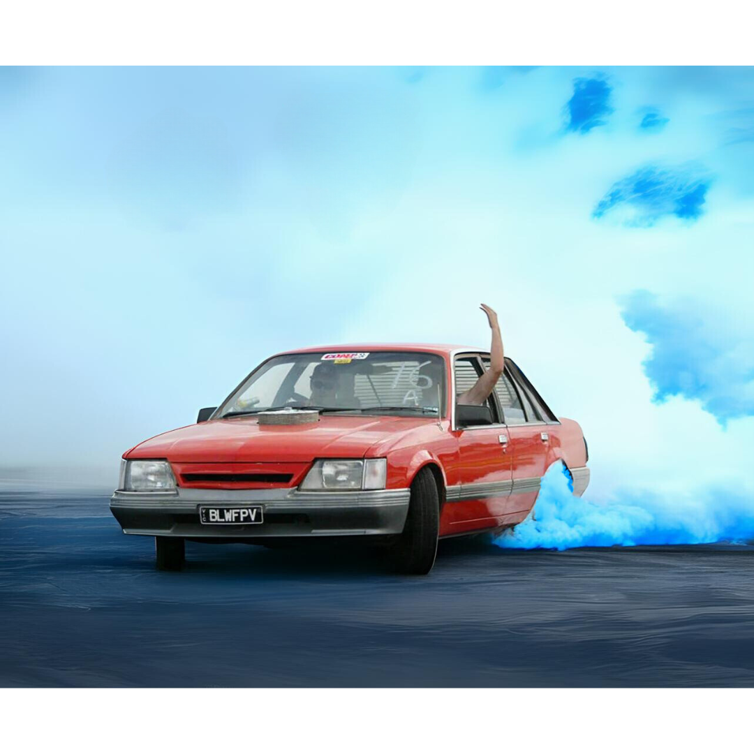 Red car performing a gender reveal burnout with blue smoke for a reveal event