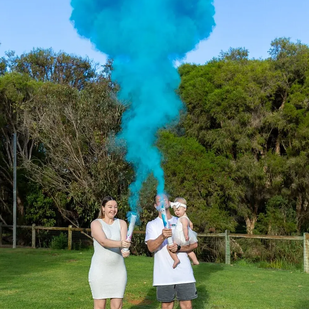 Family using Gender Reveal Powder Cannon with blue smoke in a park