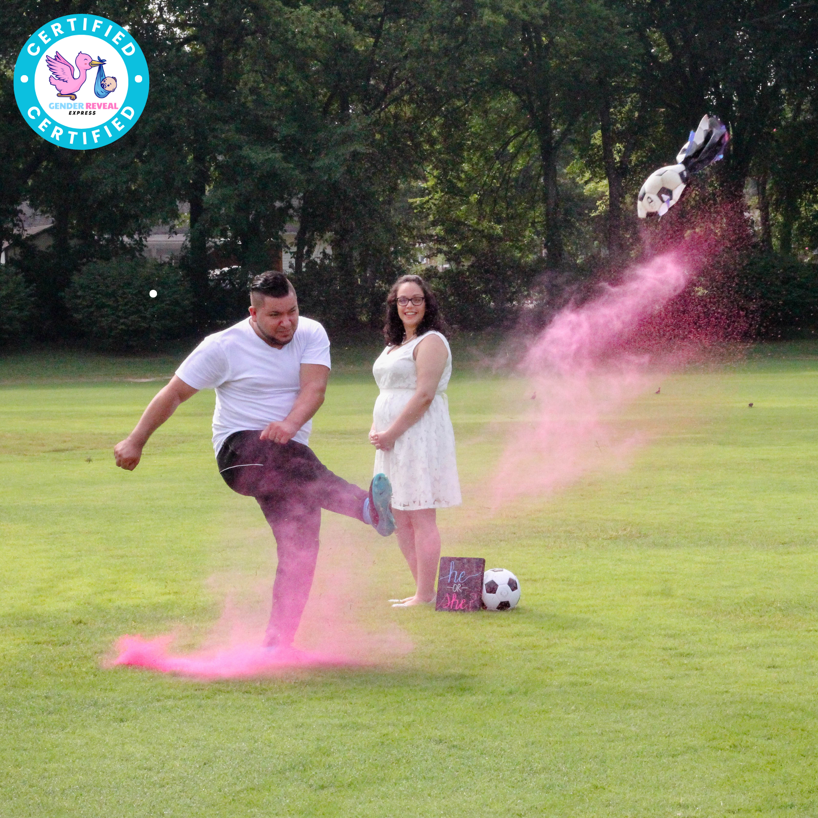 Man kicking Gender Reveal Soccer Ball with pink powder explosion while woman watches during Gender Reveal Party